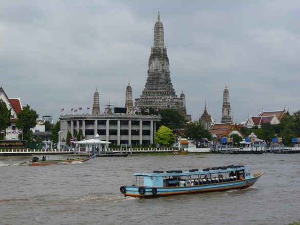 A public water taxi glides past Wat Arun on the Chao Phraya River