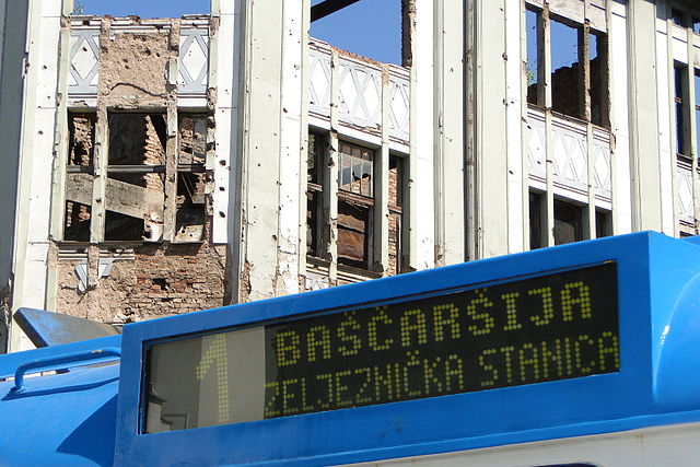 Municipal_Bus_with_Backdrop_of_War-Ruined_Building_-_Sarajevo_-_Bosnia_and_Herzegovina